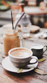 A steaming cup of rich coffee beside a bright strawberry banana smoothie on a wooden table.