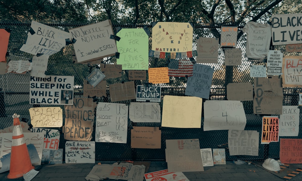 a bunch of signs that are on a fence