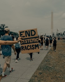 man in gray t-shirt holding black and white welcome to the beach signage