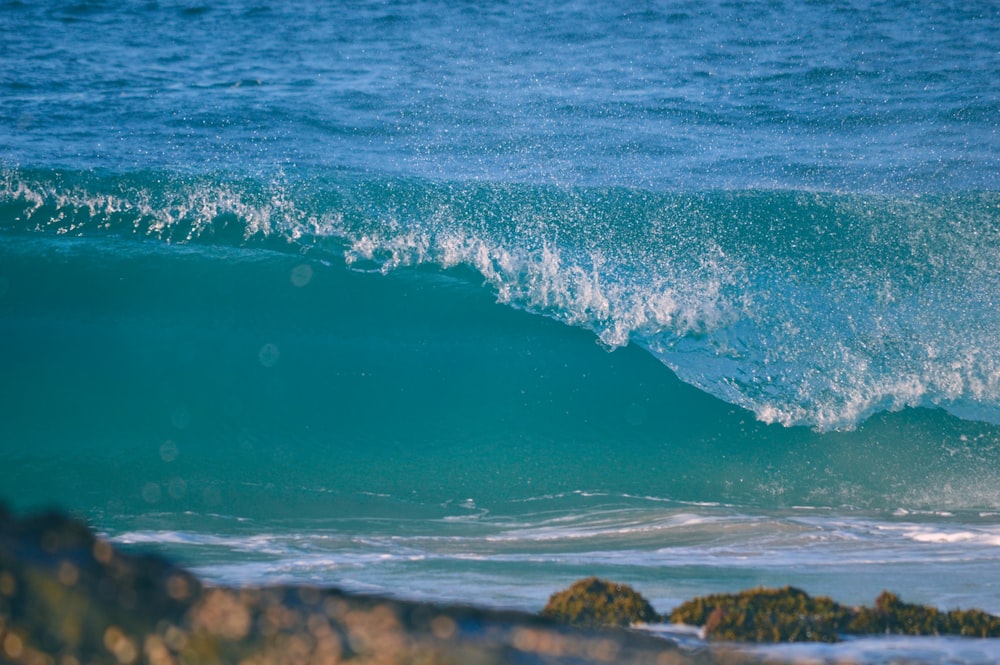 blue sea waves crashing on brown rocky shore during daytime