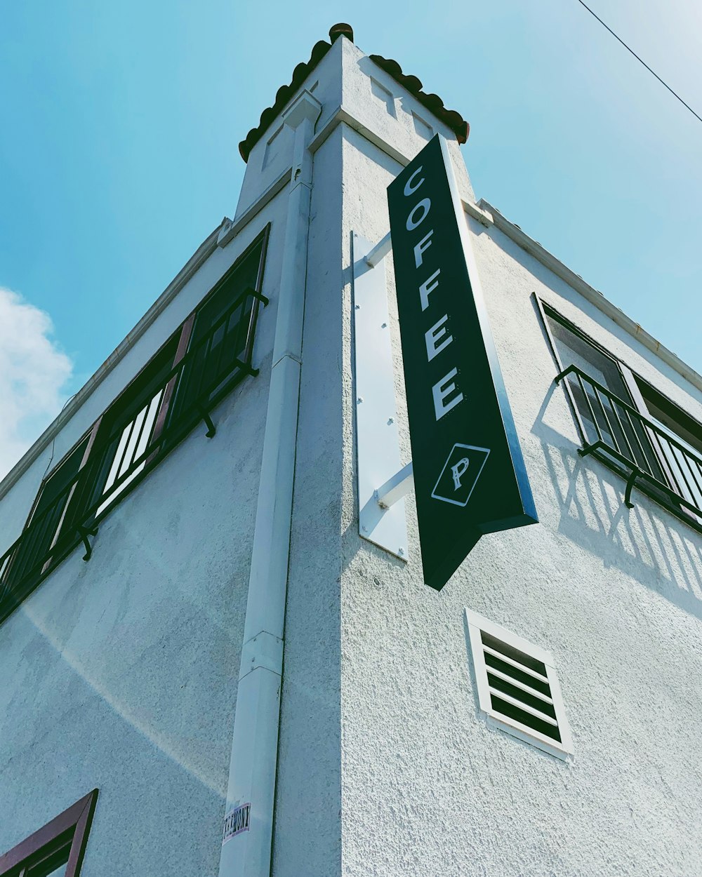 a tall white building with a green sign on it