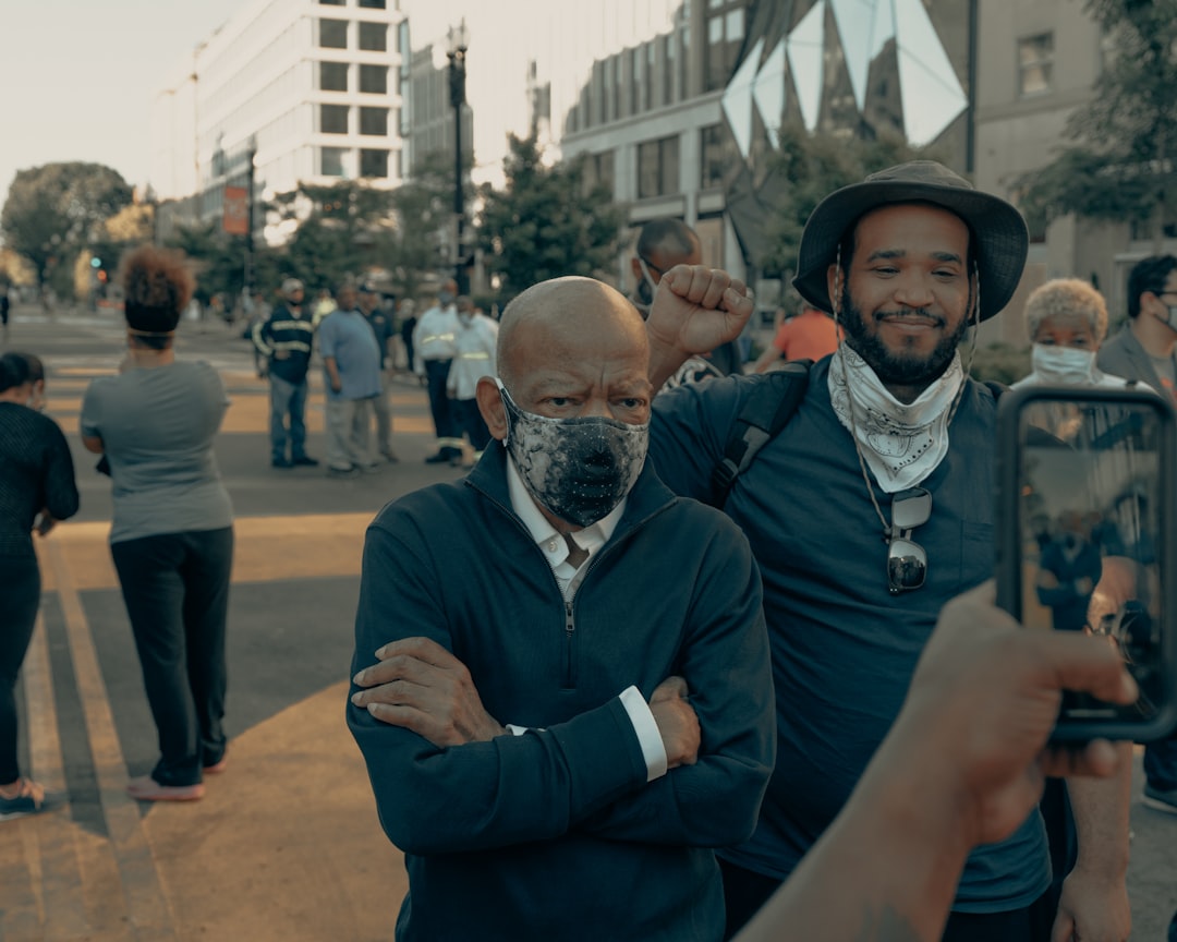man in blue suit jacket standing beside woman in gray hijab, U.S. Representative John Lewis poses for a photo at Black L