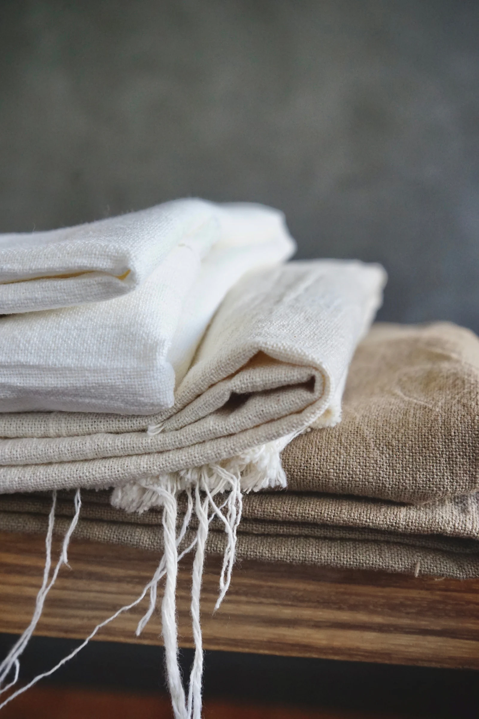 Unbleached white linen folded on a wooden surface.