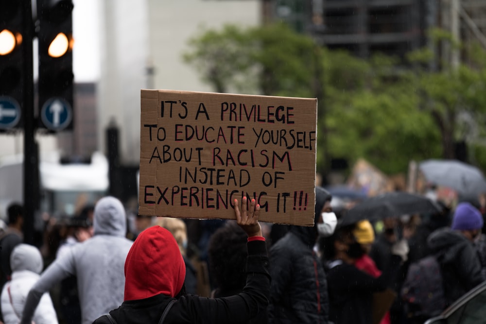 people holding brown wooden signage during daytime