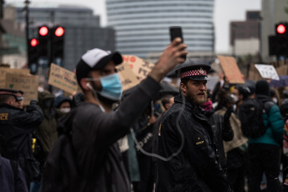 homme en veste noire tenant un smartphone