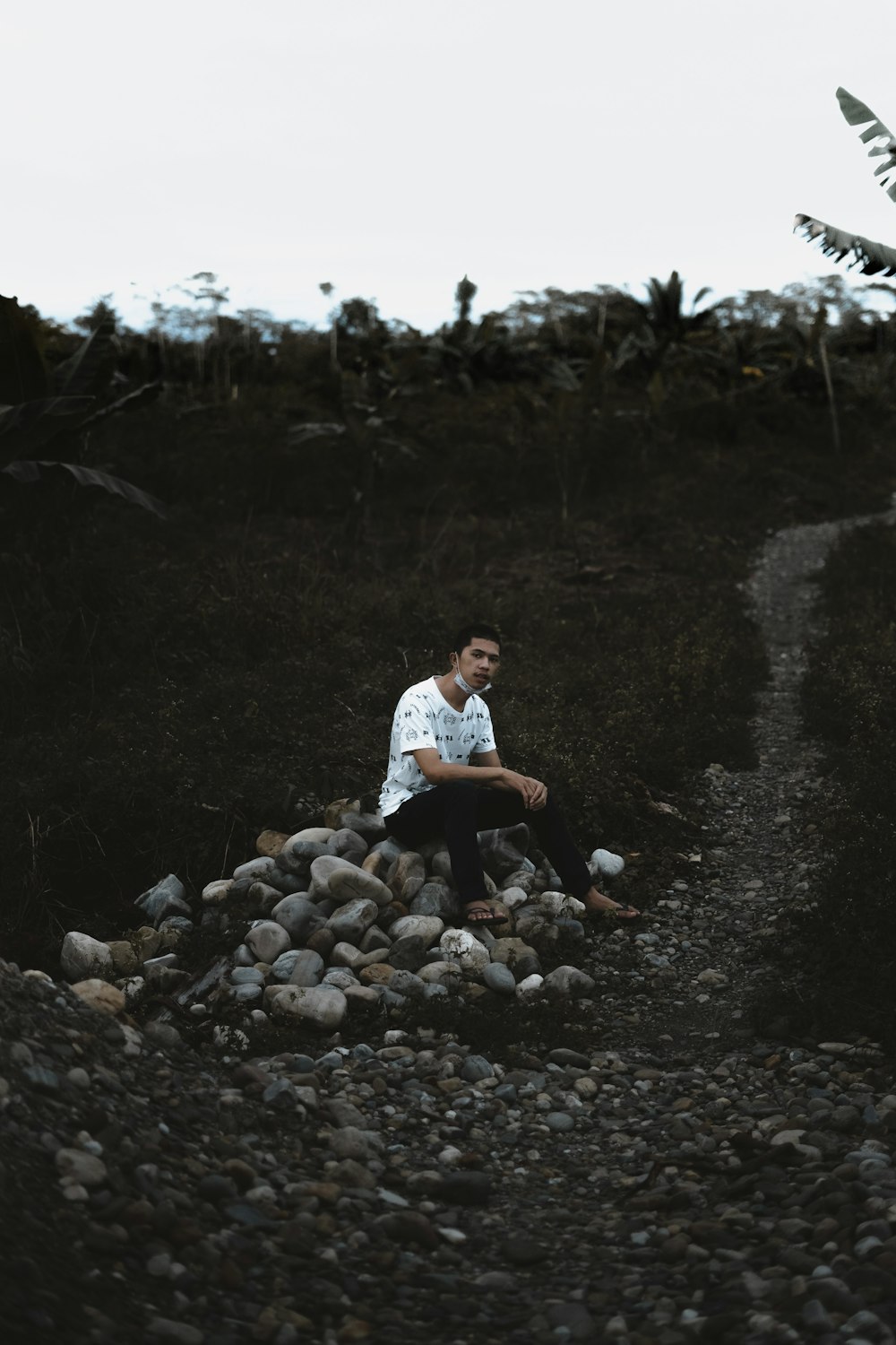 man in white dress shirt and black pants sitting on rocky ground