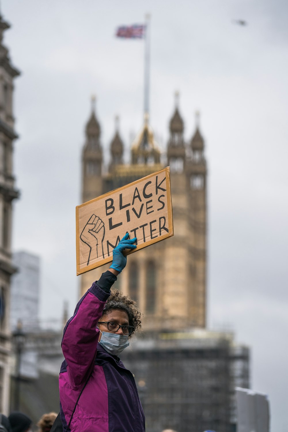 woman in purple jacket holding blue and white signage