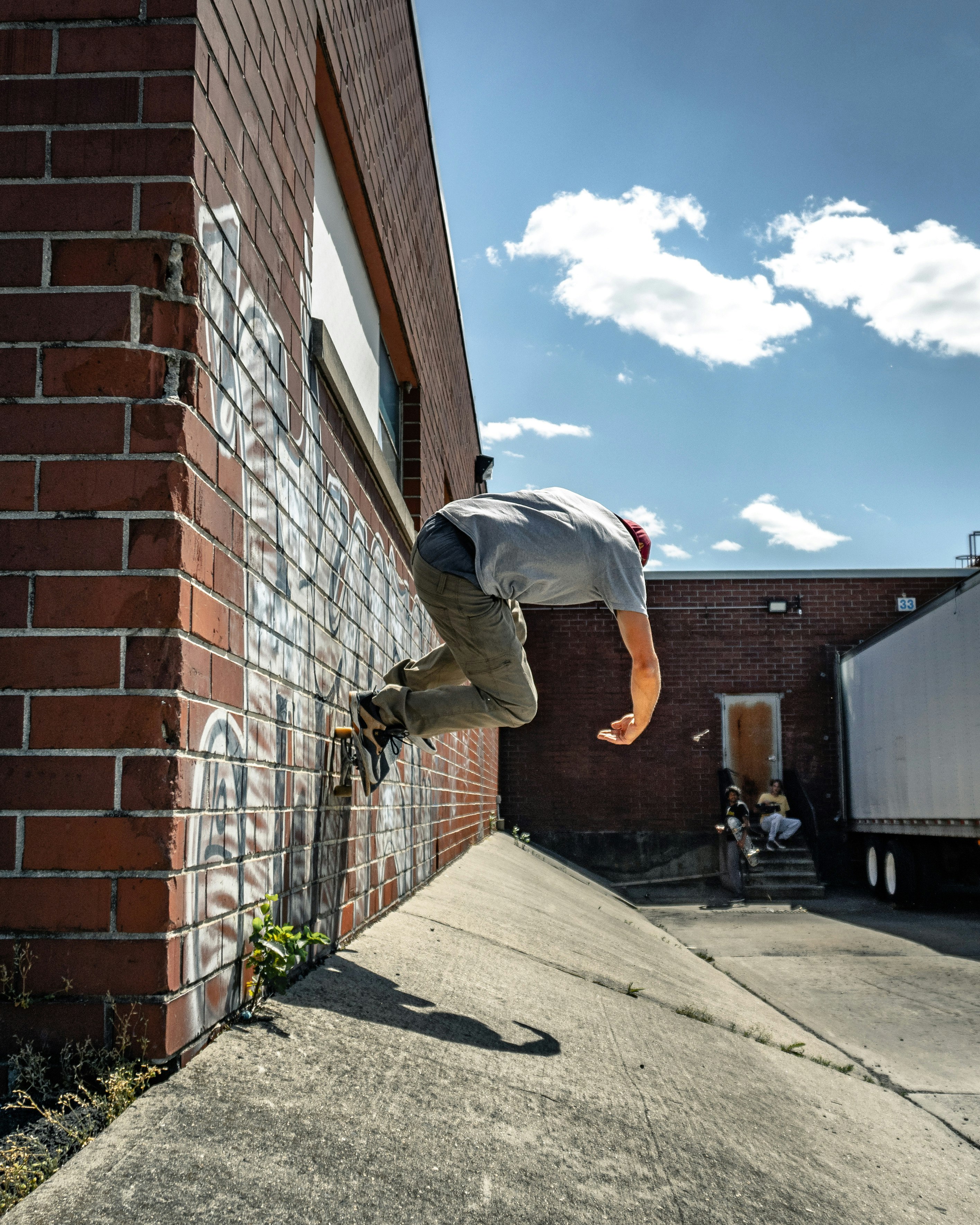 man in white shirt and gray pants jumping on brown brick wall during daytime