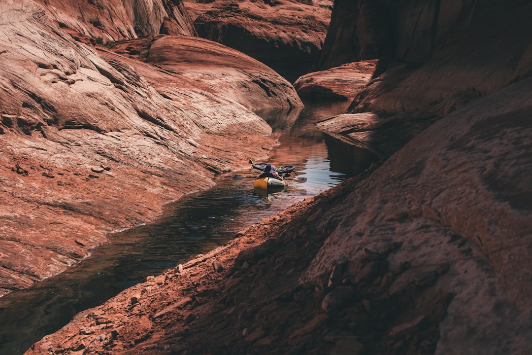 person in blue shirt sitting on rock near body of water during daytime