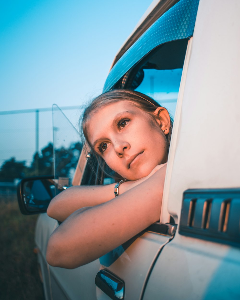 woman in white tank top leaning on white car during daytime