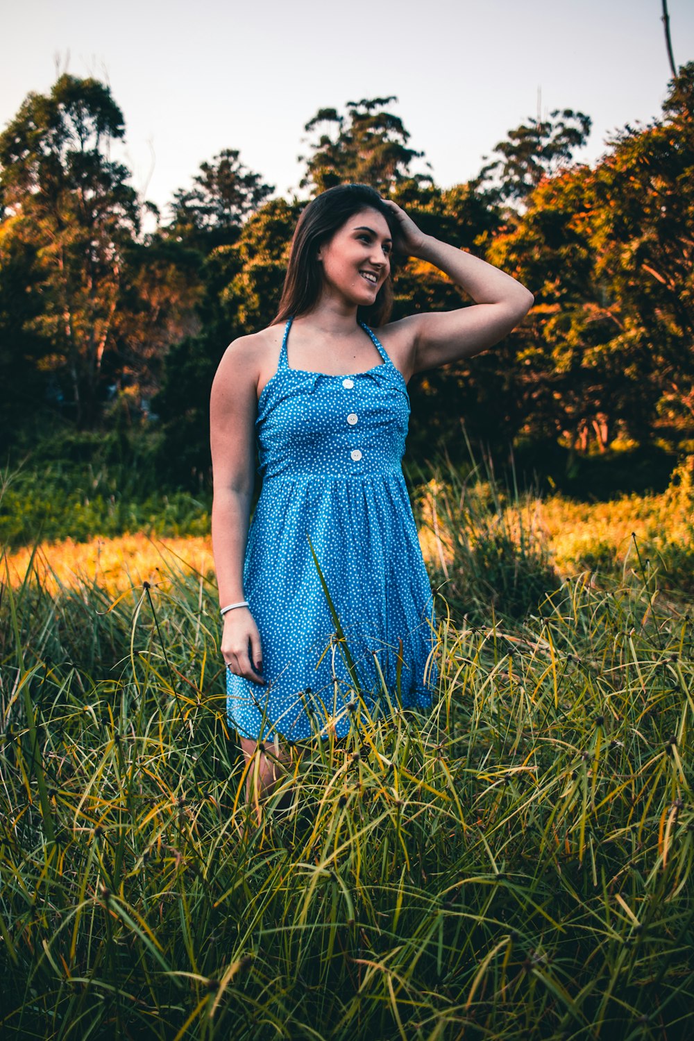 woman in blue and white polka dot spaghetti strap dress standing on green grass field during
