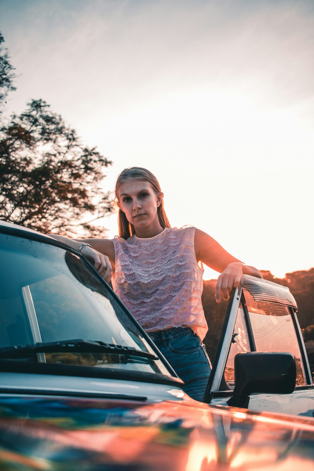 woman in white lace tank top sitting on black car