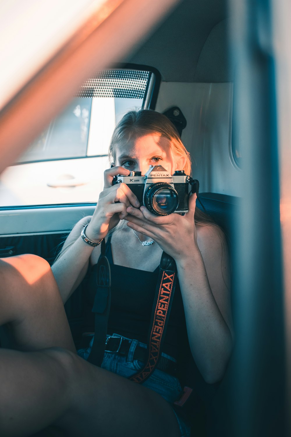 woman in blue tank top holding black dslr camera