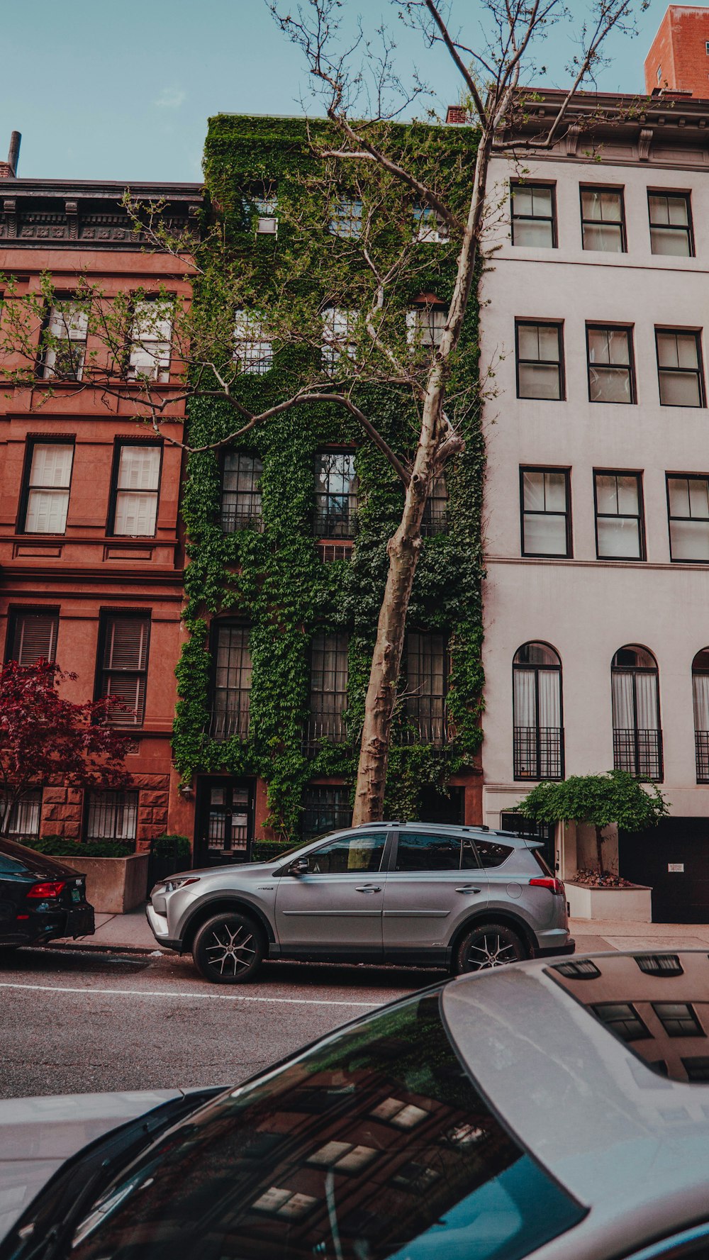 silver sedan parked beside brown concrete building during daytime