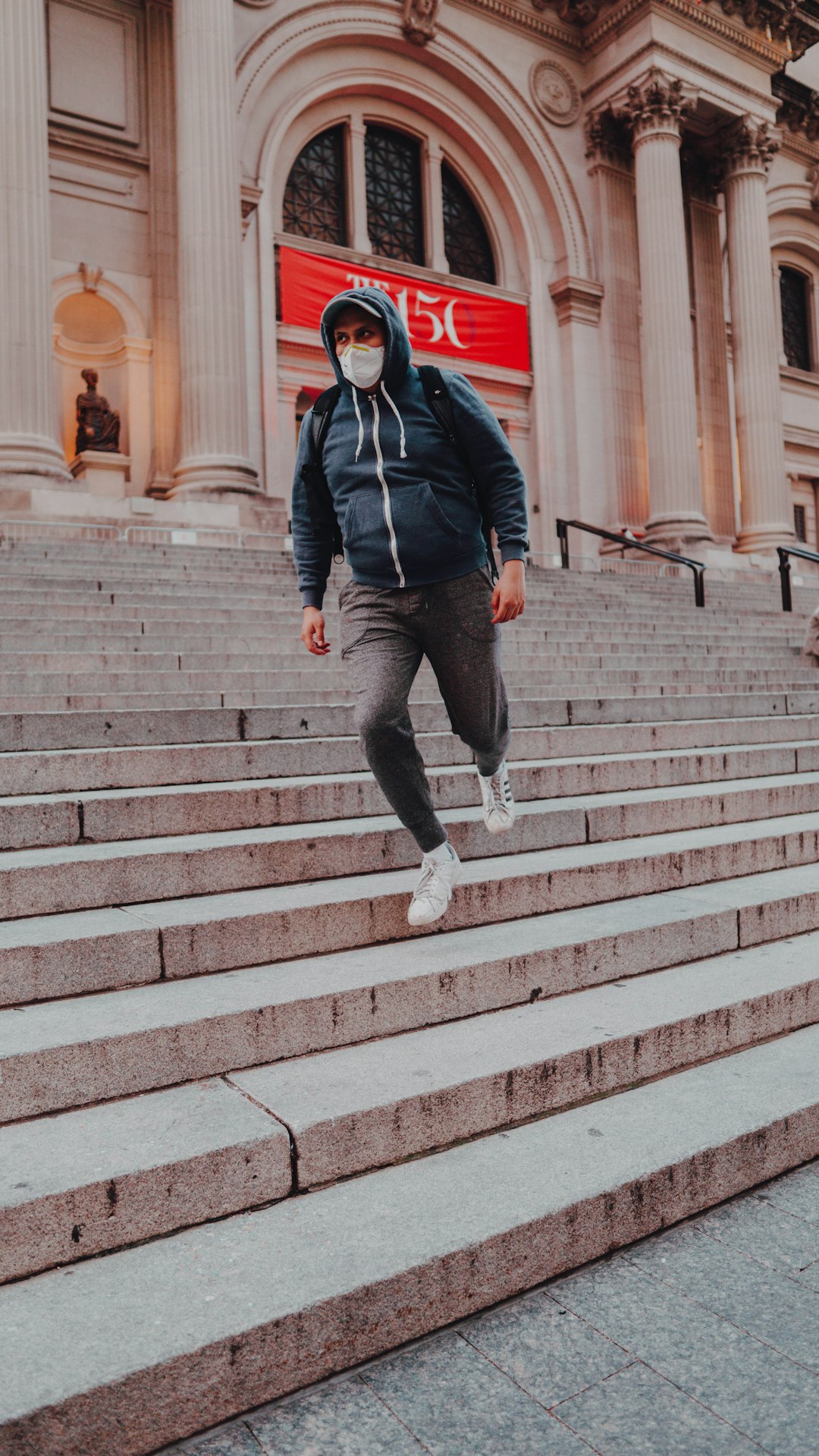 man in black jacket and gray pants walking on gray concrete stairs