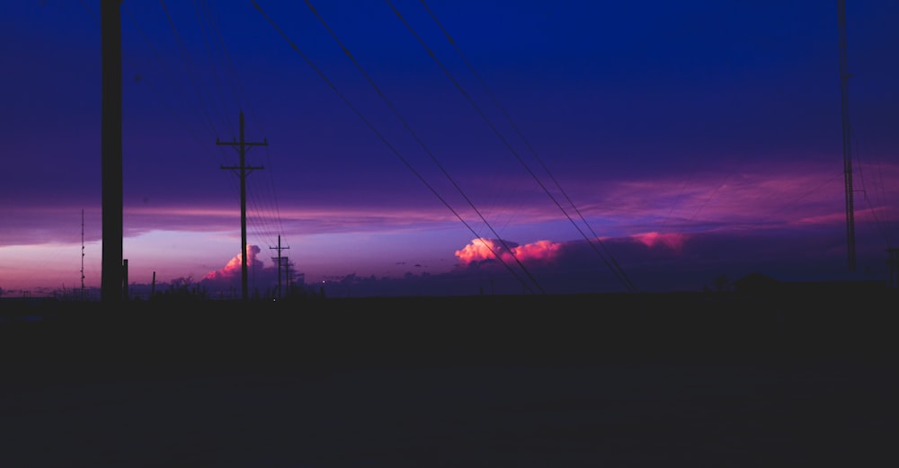 silhouette of electric post under orange and blue sky