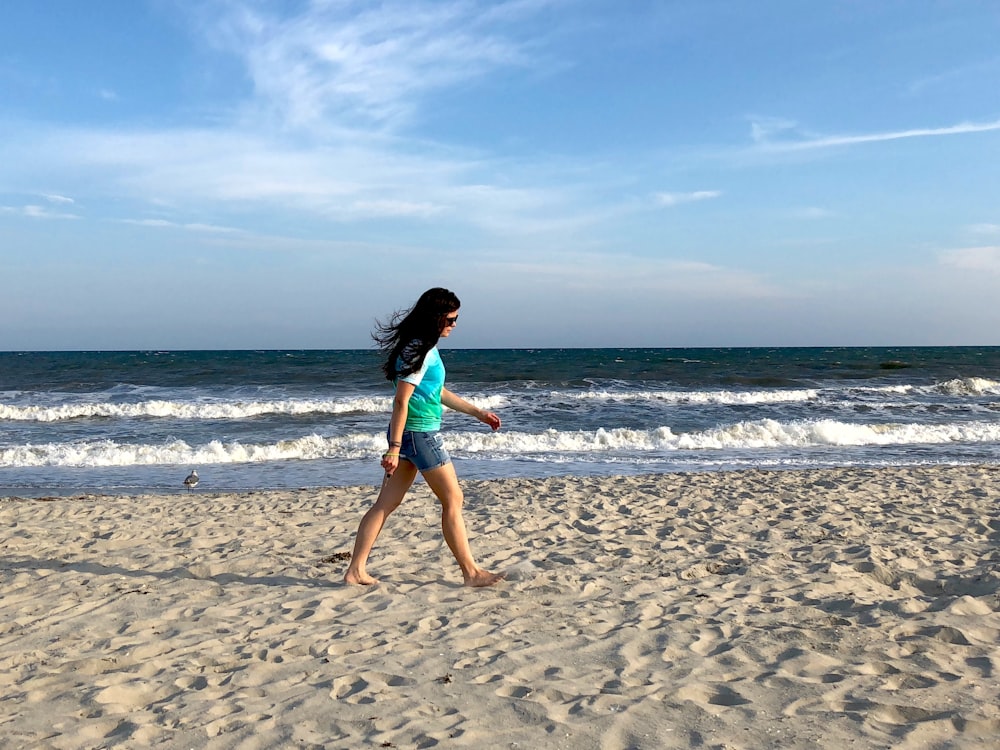 woman in blue tank top running on beach during daytime