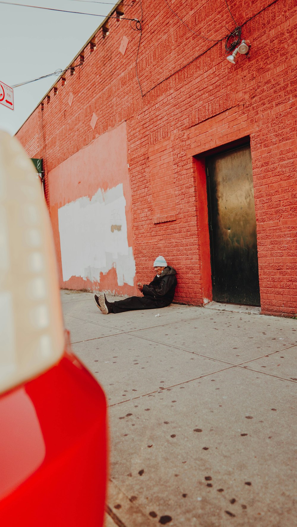 man in black jacket sitting on sidewalk during daytime