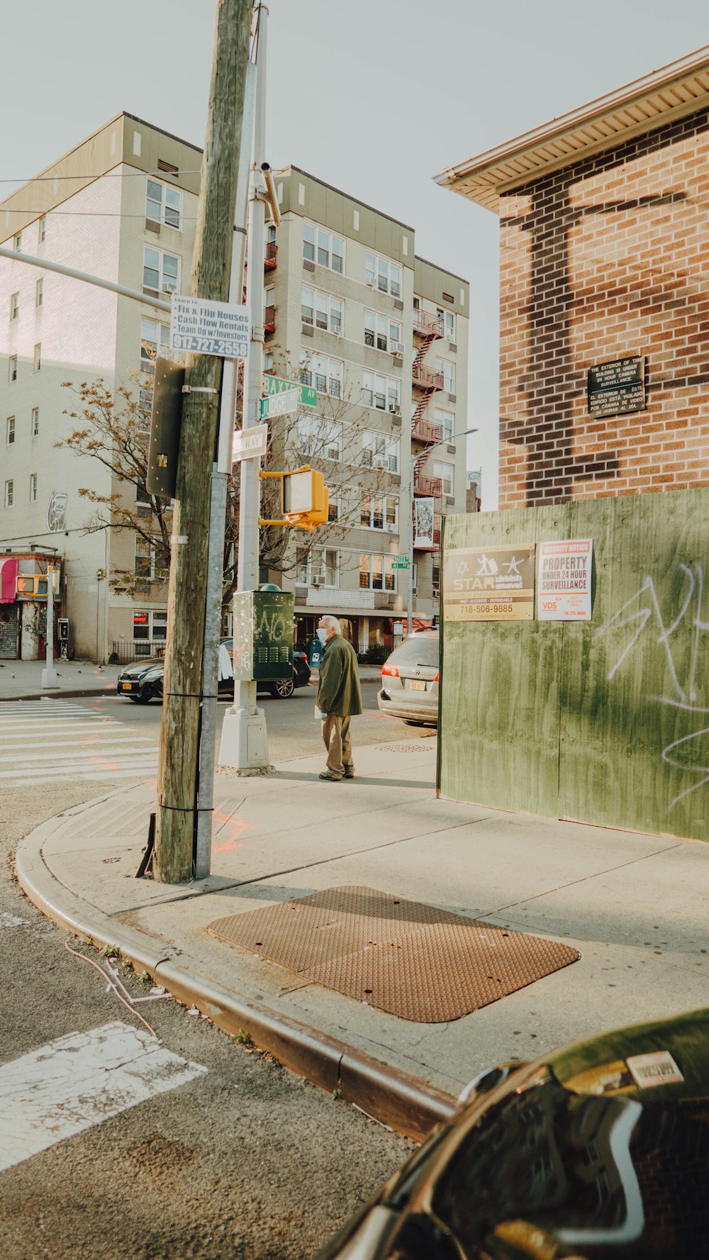 man in green jacket walking on sidewalk during daytime