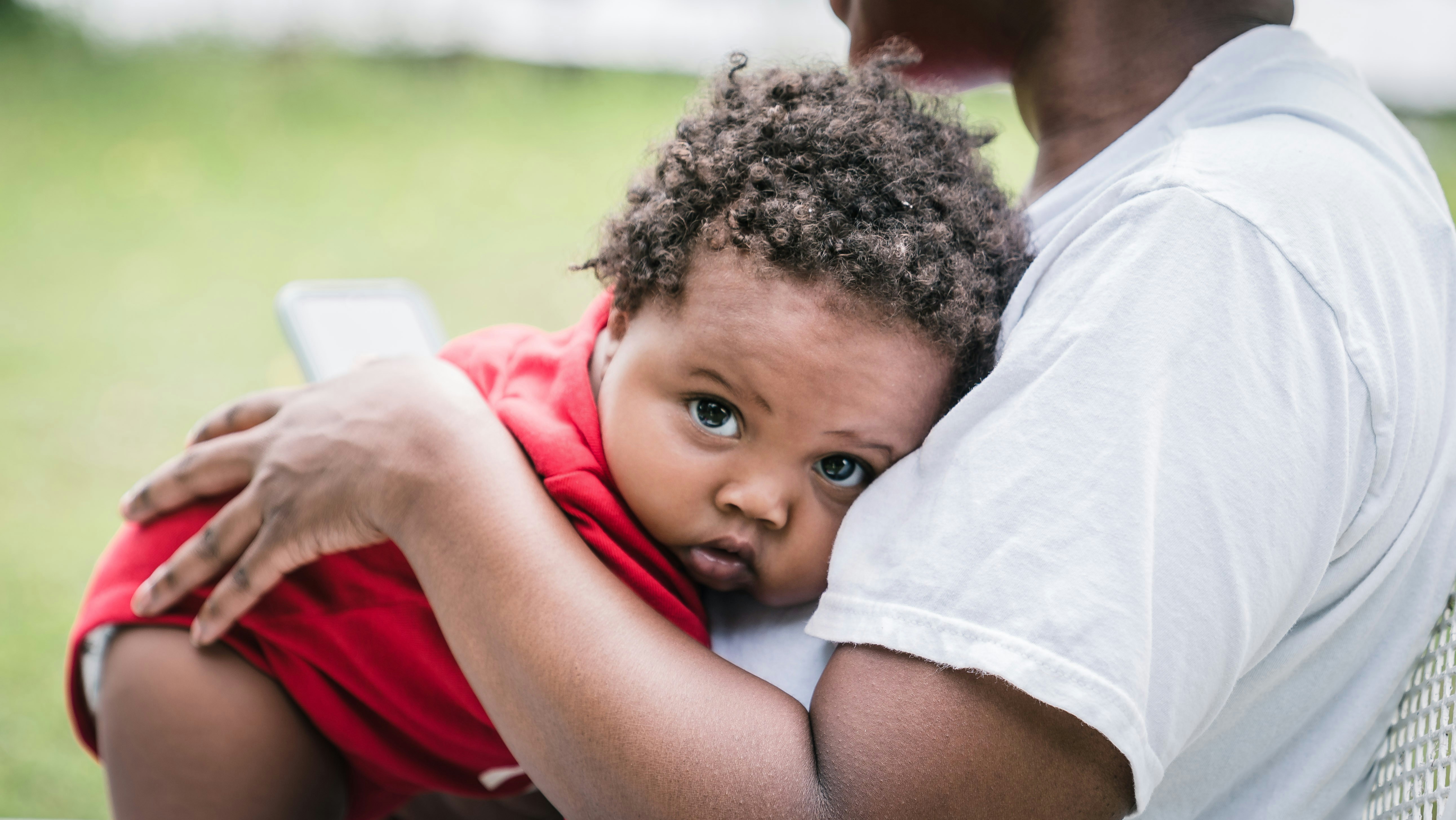 menino na camisa vermelha deitado no homem na camisa branca