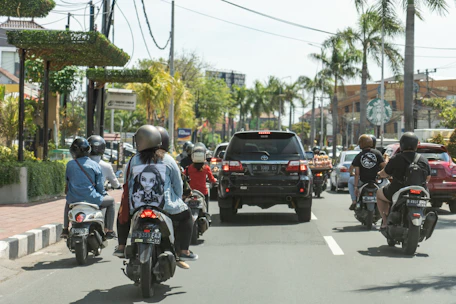 A group of friends enjoying scooters along a vibrant Balinese street market.