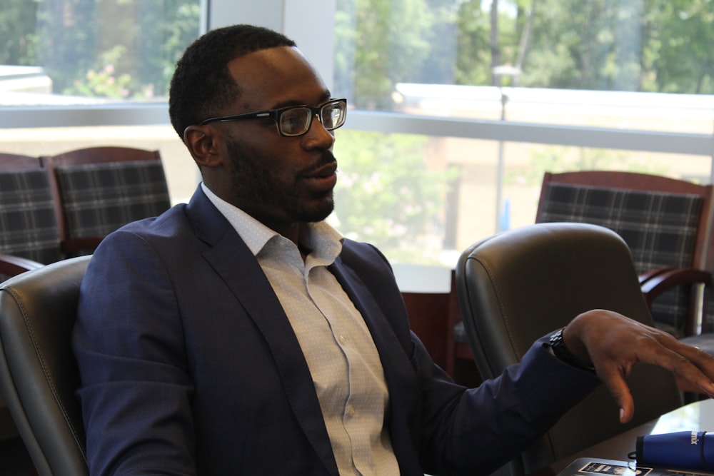 man in black suit jacket wearing eyeglasses