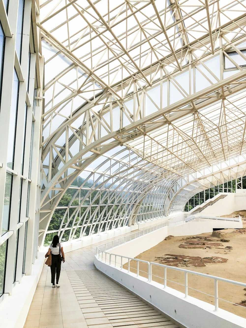 woman in black shirt walking on white concrete hallway