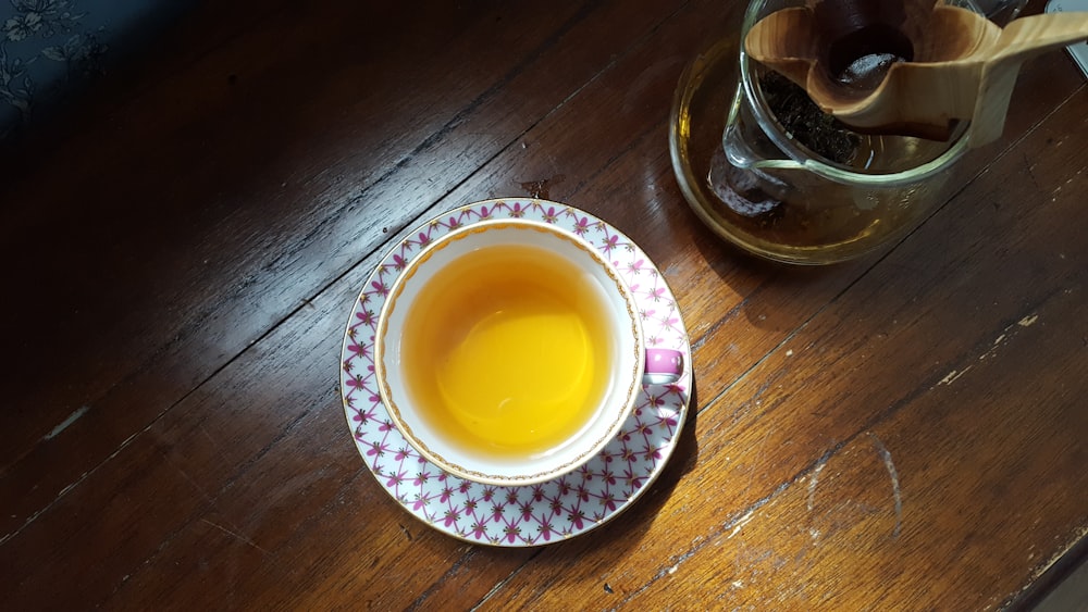 흰색과 파란색 세라믹 접시에 노란색 액체가 있는 투명 유리 컵