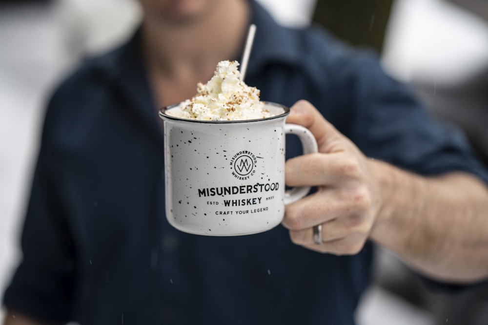 person holding white ceramic mug with white cream