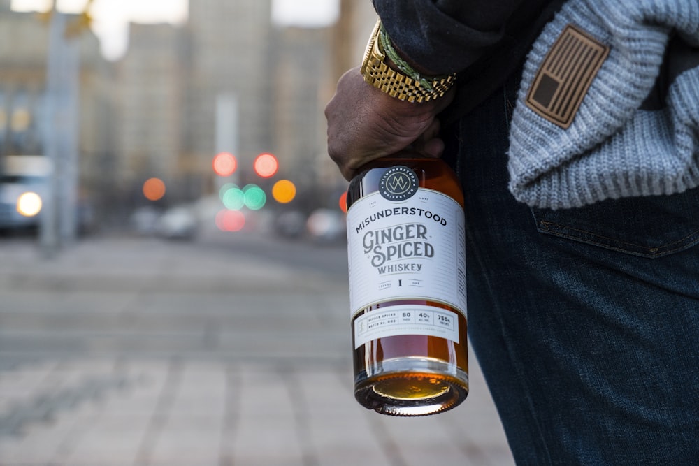 person holding white and brown labeled bottle