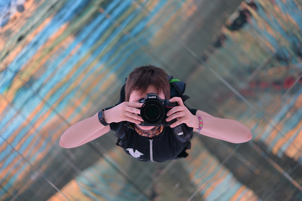 man in black t-shirt holding black nikon dslr camera