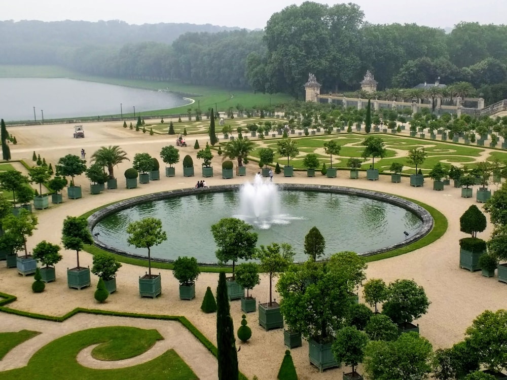 green trees and green grass field with fountain during daytime