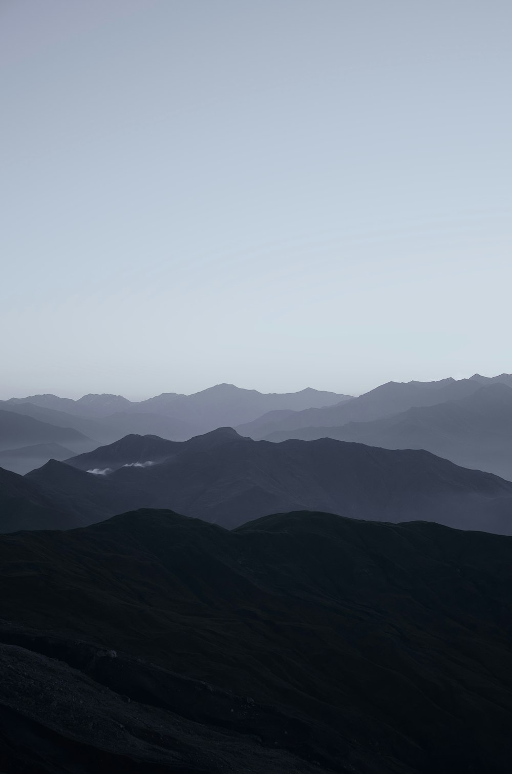 Montañas negras bajo el cielo blanco durante el día