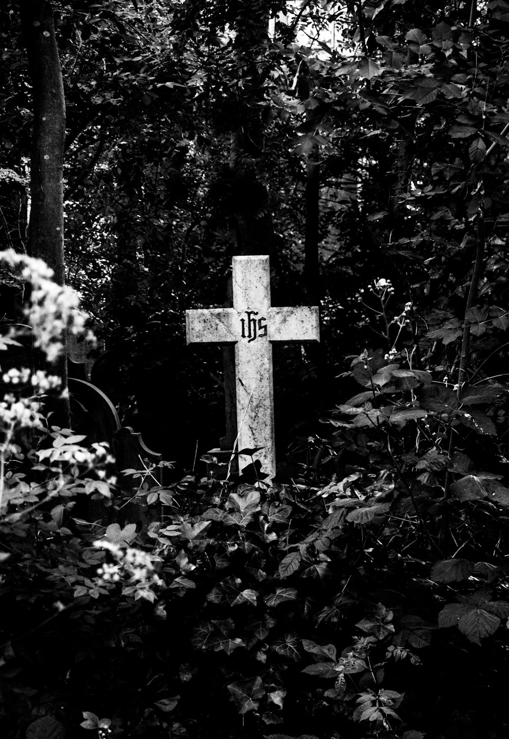 grayscale photo of cross surrounded by trees