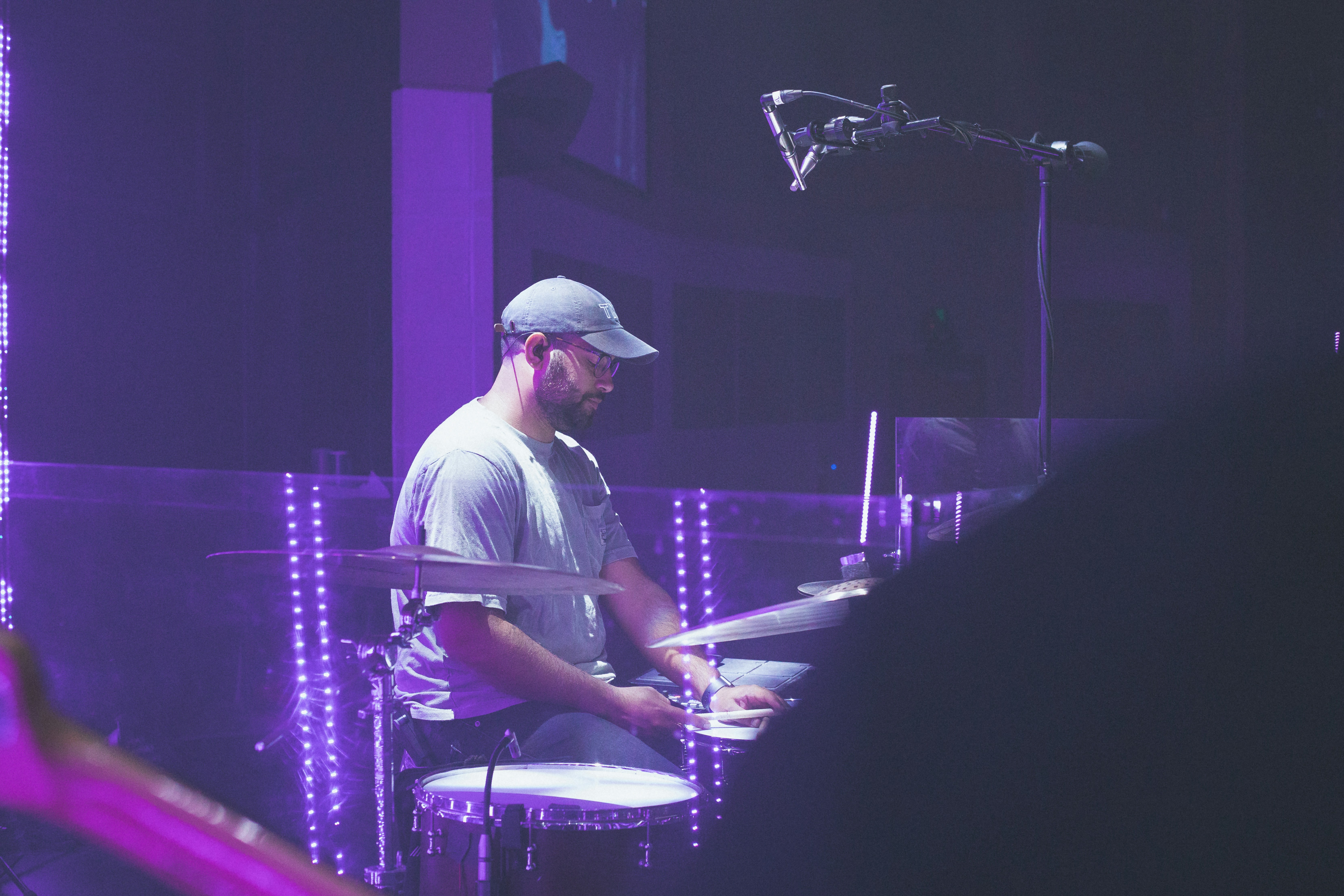 man in white shirt playing drum set