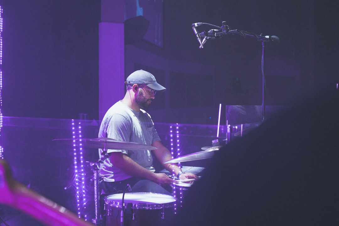 man in white shirt playing drum set