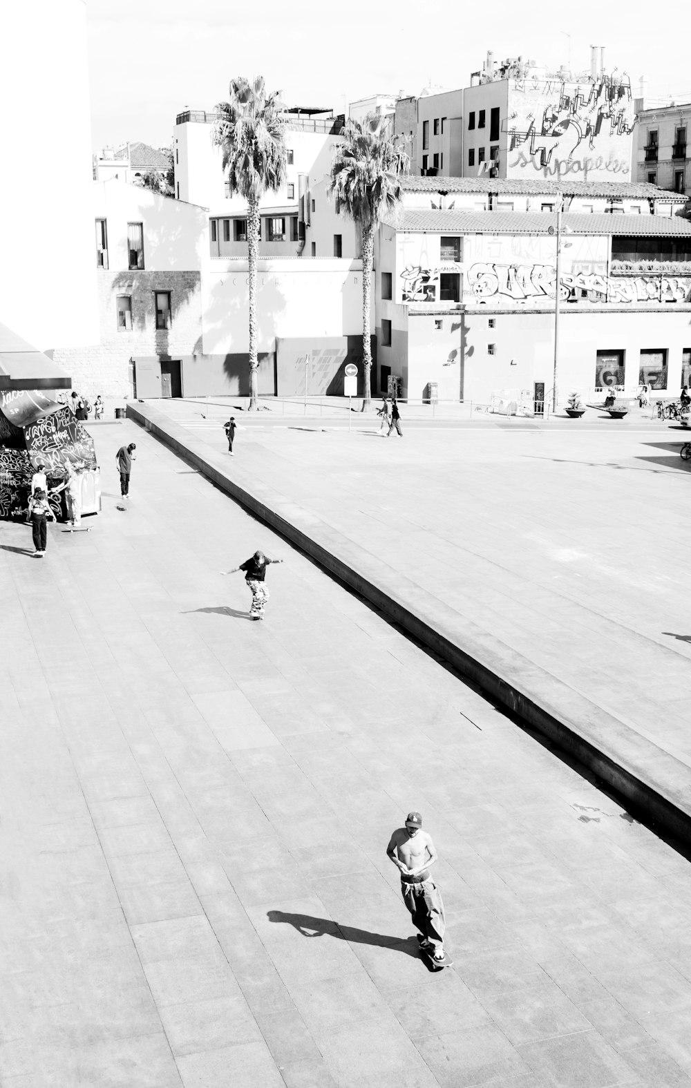 grayscale photo of man in black jacket and pants walking on sidewalk