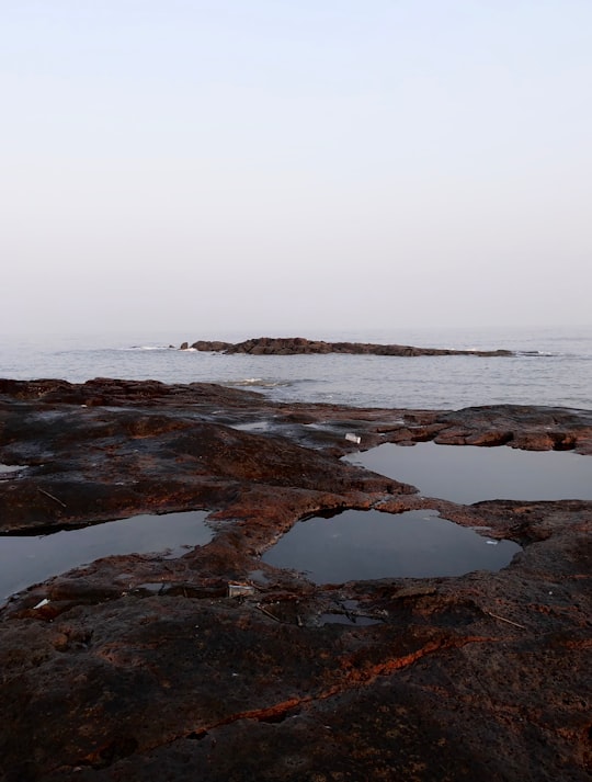 brown rock formation on sea under white sky during daytime in Malad West India