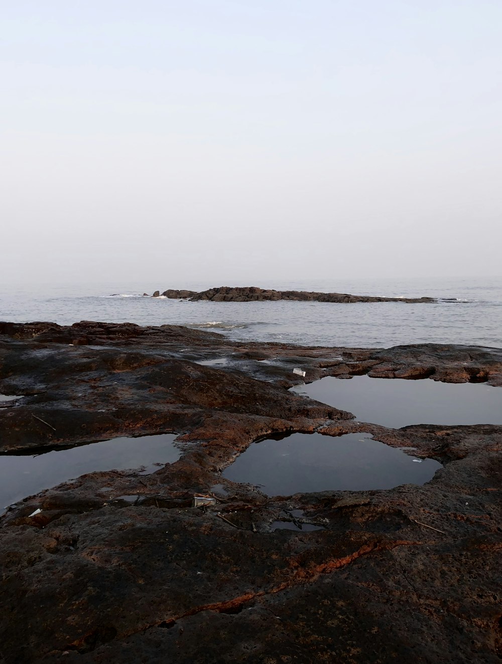 brown rock formation on sea under white sky during daytime