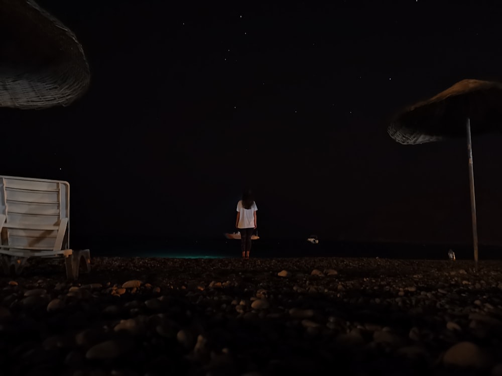 man in white shirt standing on brown sand during night time