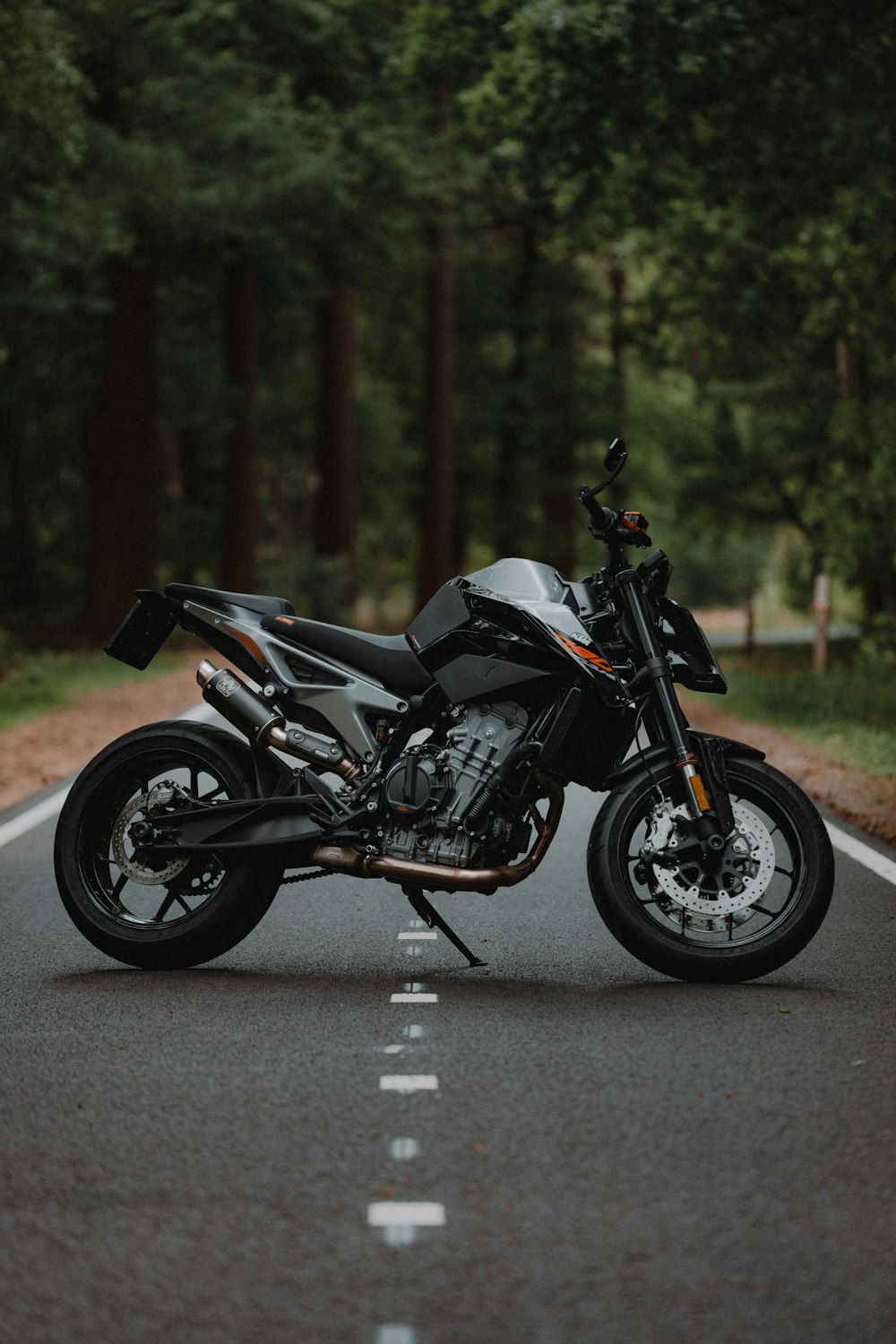 昼間の道路上の黒と銀の裸のオートバイ