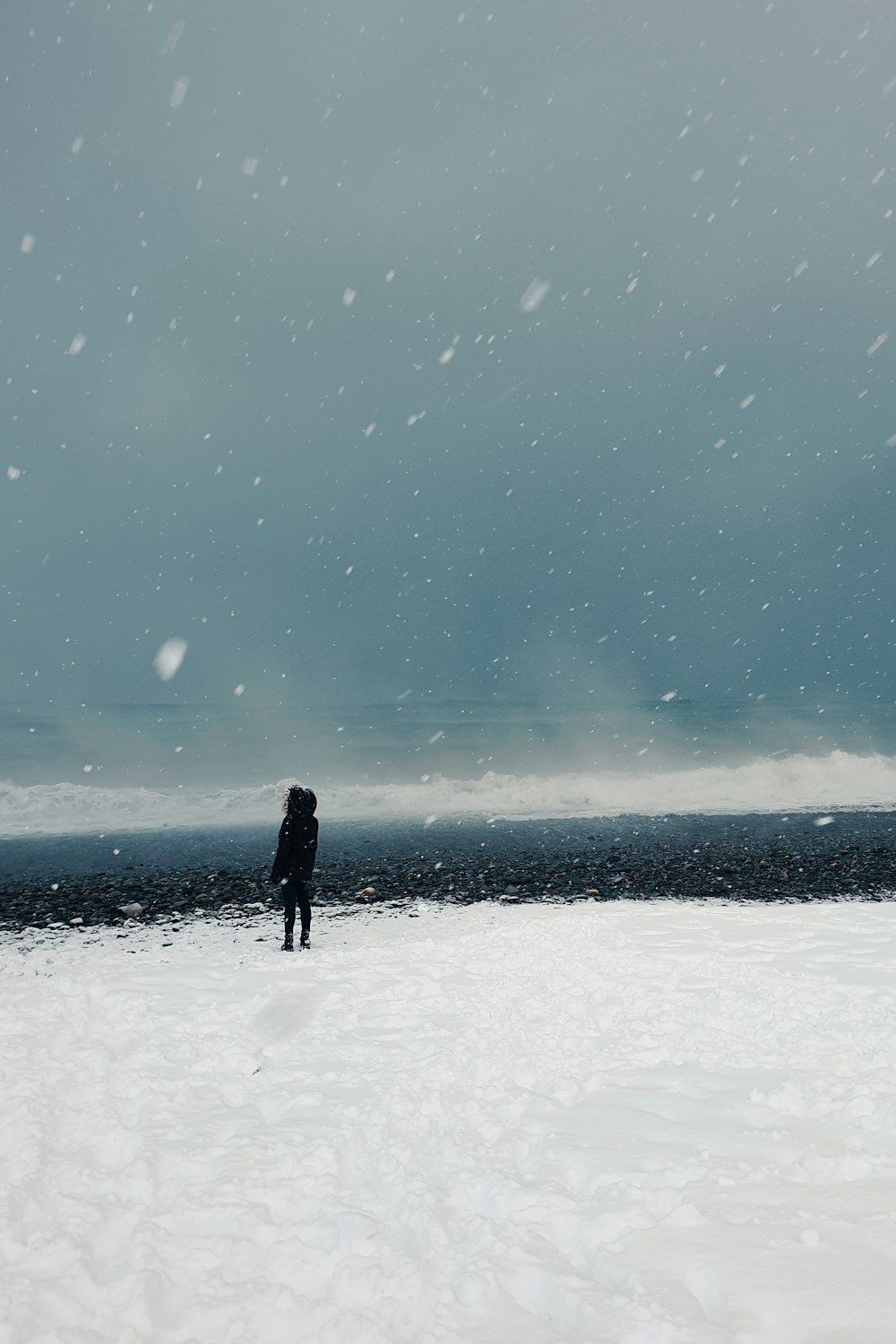 person in black jacket standing on snow covered ground under blue sky during daytime