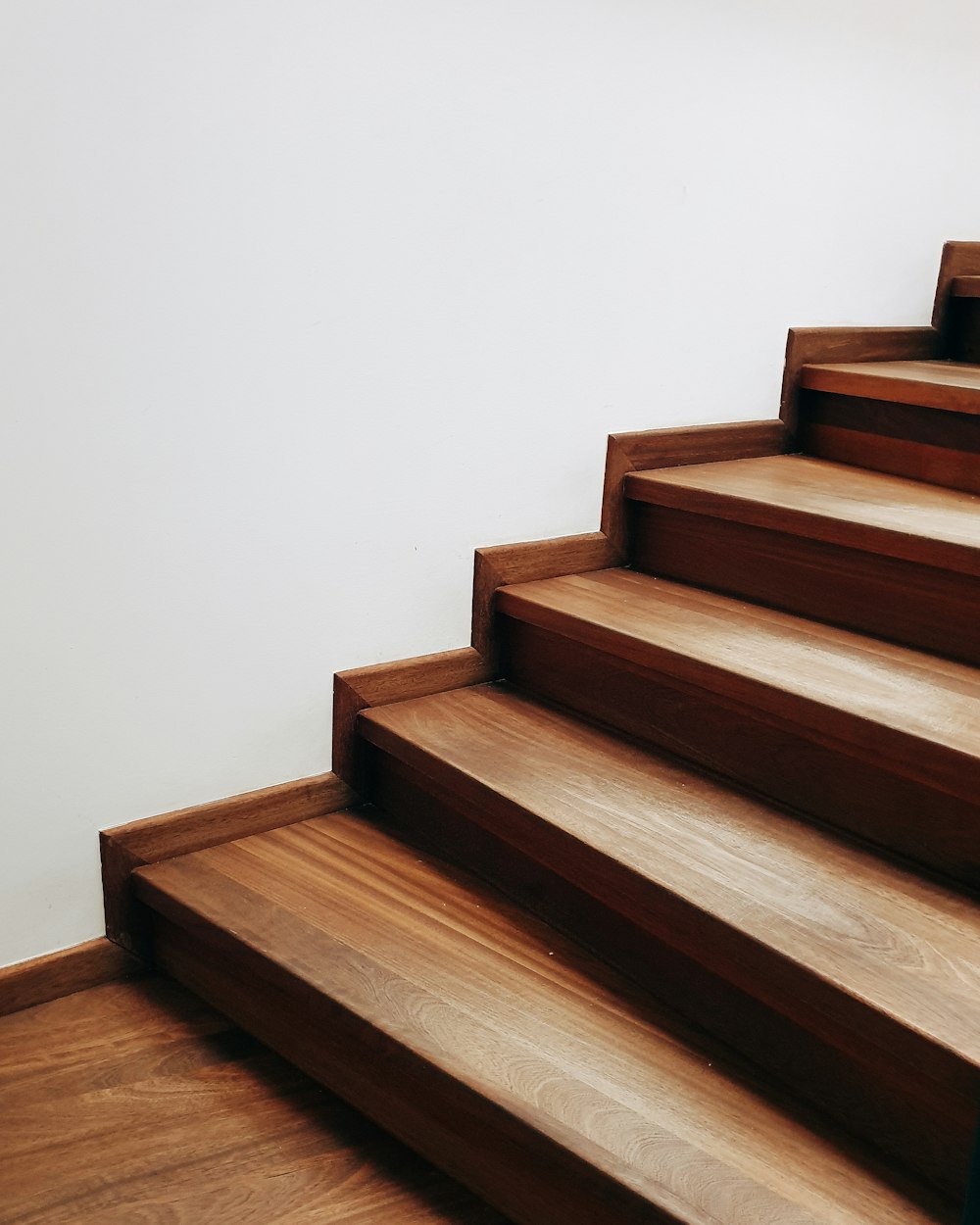 escalera de madera marrón cerca de la pared blanca