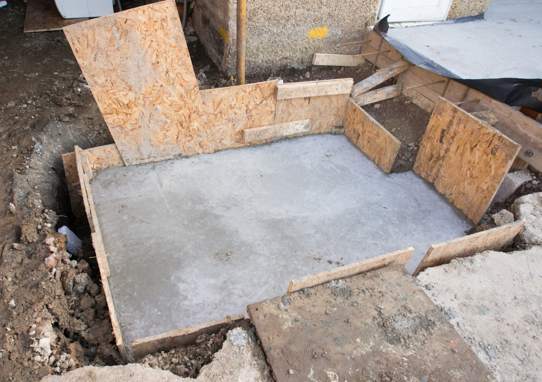 Fresh wet concrete pad contained in amber wooden form boards at a residential site