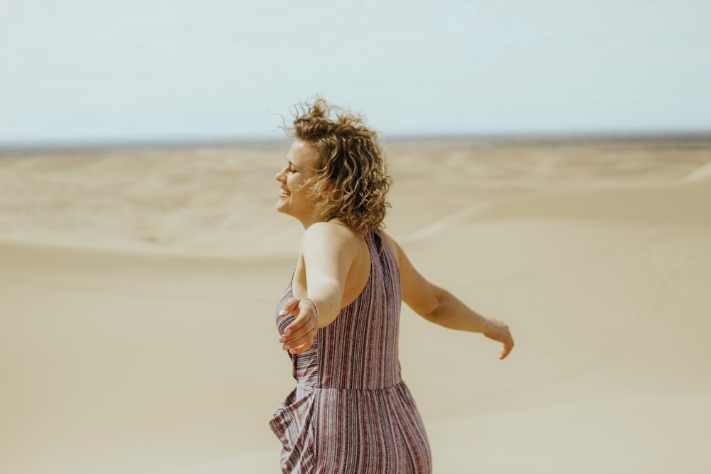 woman in white and purple stripe tank dress standing on brown sand during daytime