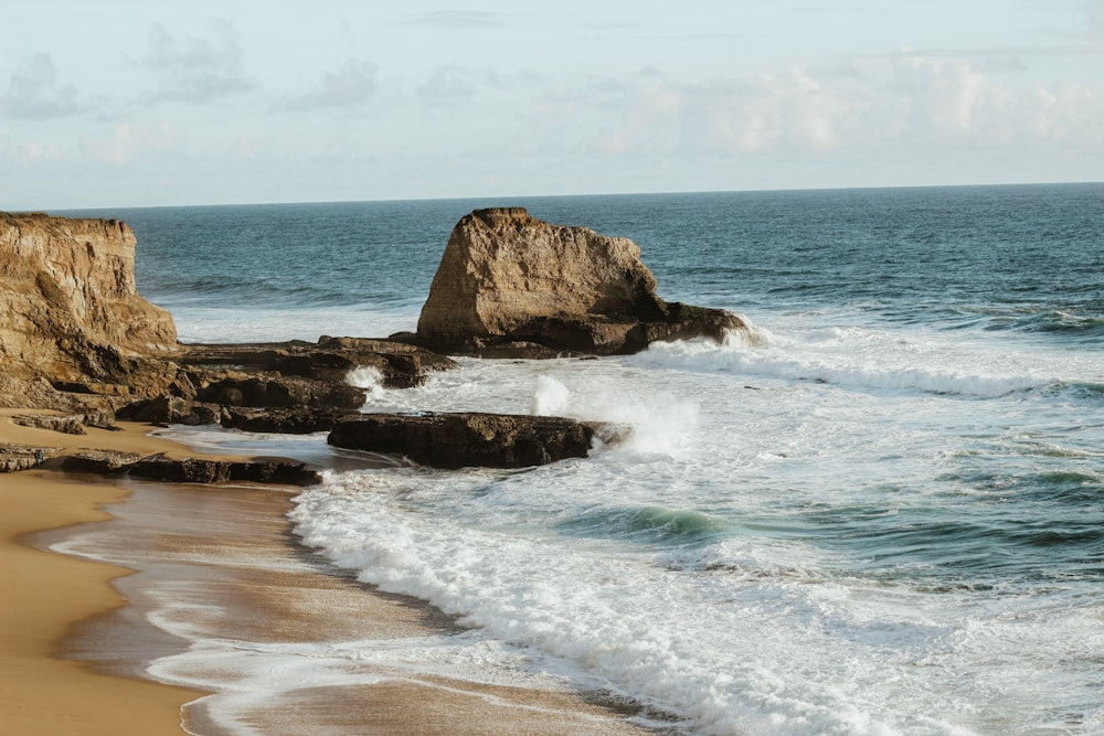 Formación rocosa marrón en la orilla del mar durante el día