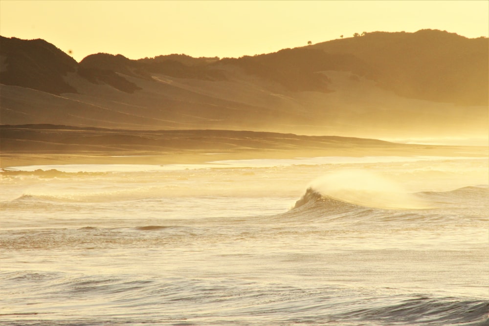 ocean waves crashing on shore during sunset