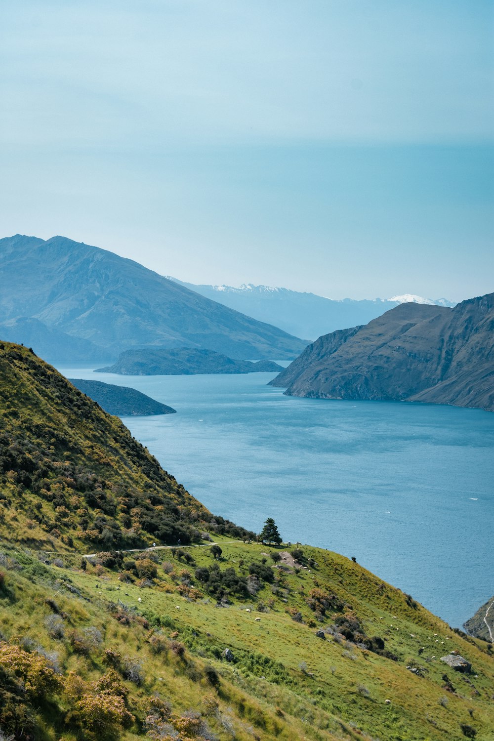 montagne verte et brune à côté d’un plan d’eau pendant la journée