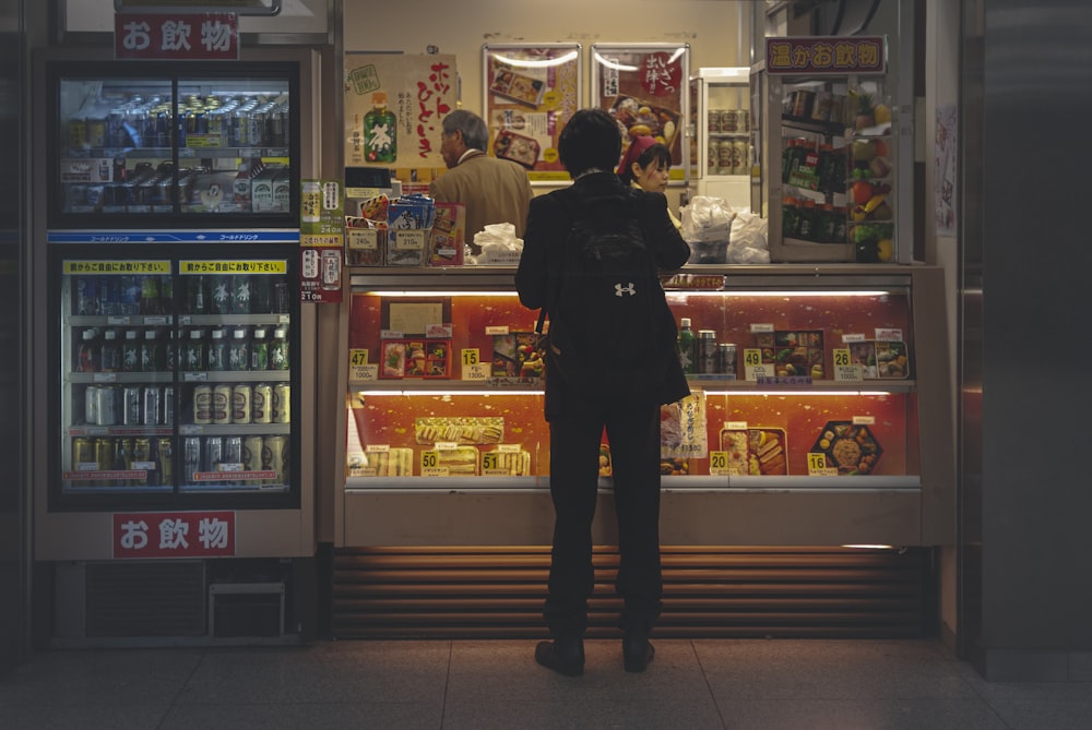 man in black jacket standing near the store