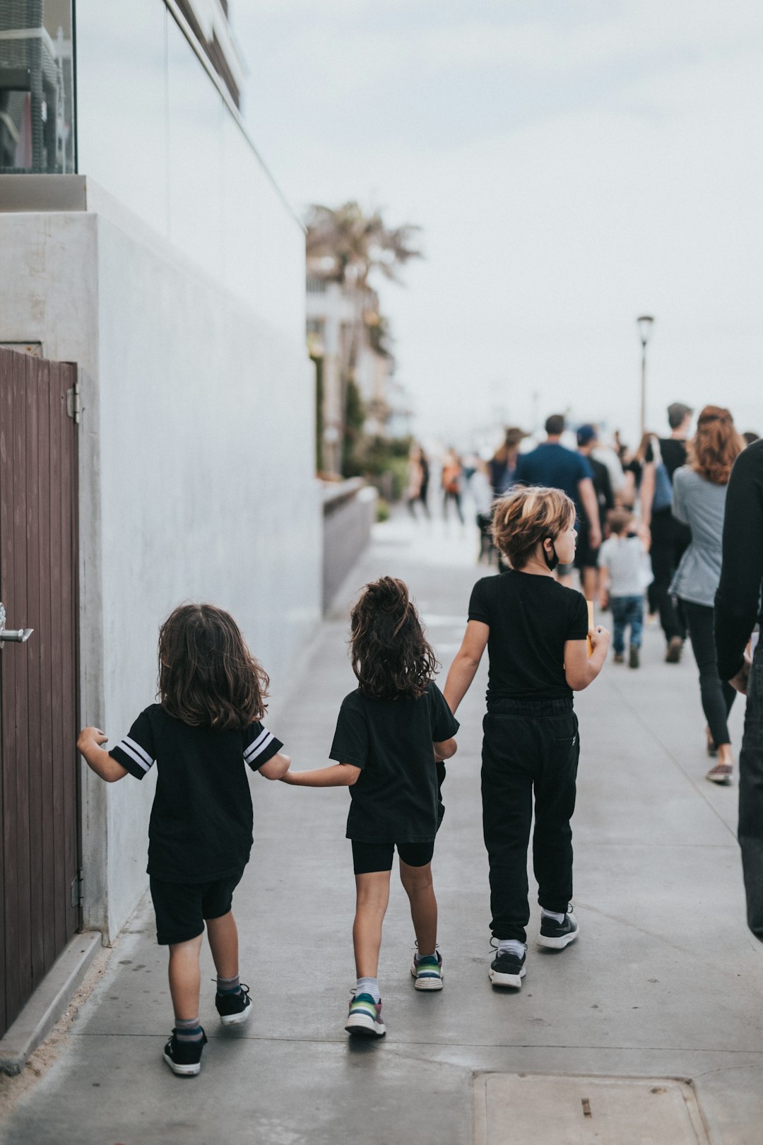 girl in black t-shirt and black shorts walking on sidewalk during daytime